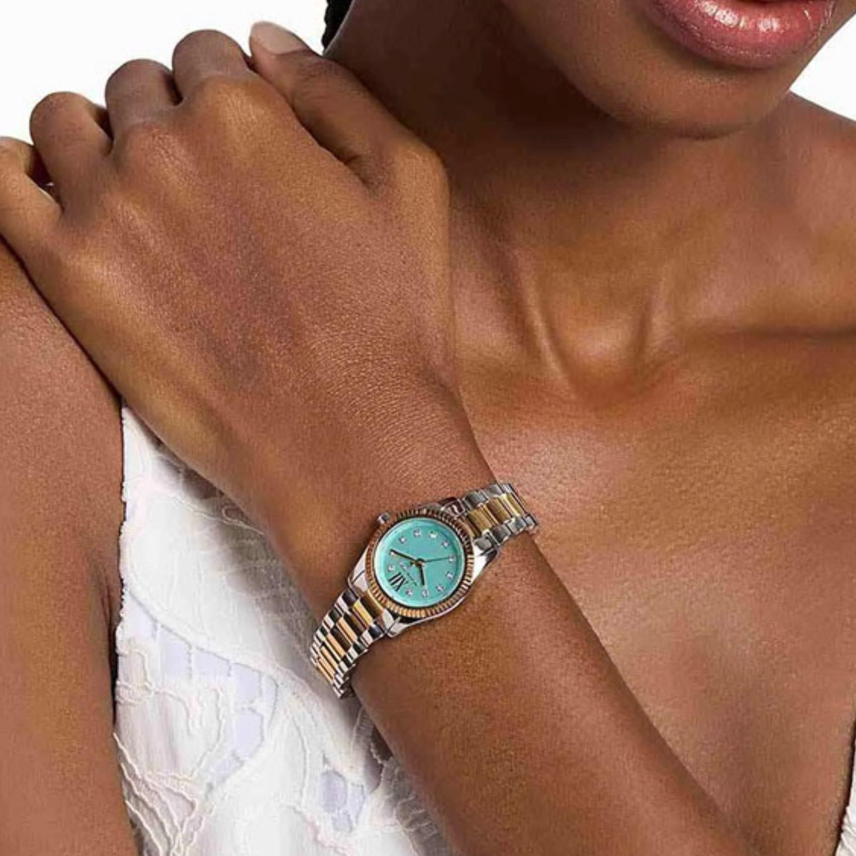 Γυναικείο ρολόι Michael Kors Lexington MK7579 με ασημί-χρυσό μπρασελέ και τιρκουάζ καντράν φορεμένο στον καρπό