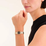 Γυναικείο ρολόι Rosefield Boxelle Black Crystals Frame BBGSG-B09 με χρύσο μπρασελέ και μαύρο τετράγωνο καντράν με πέτρες, φορεμένο.