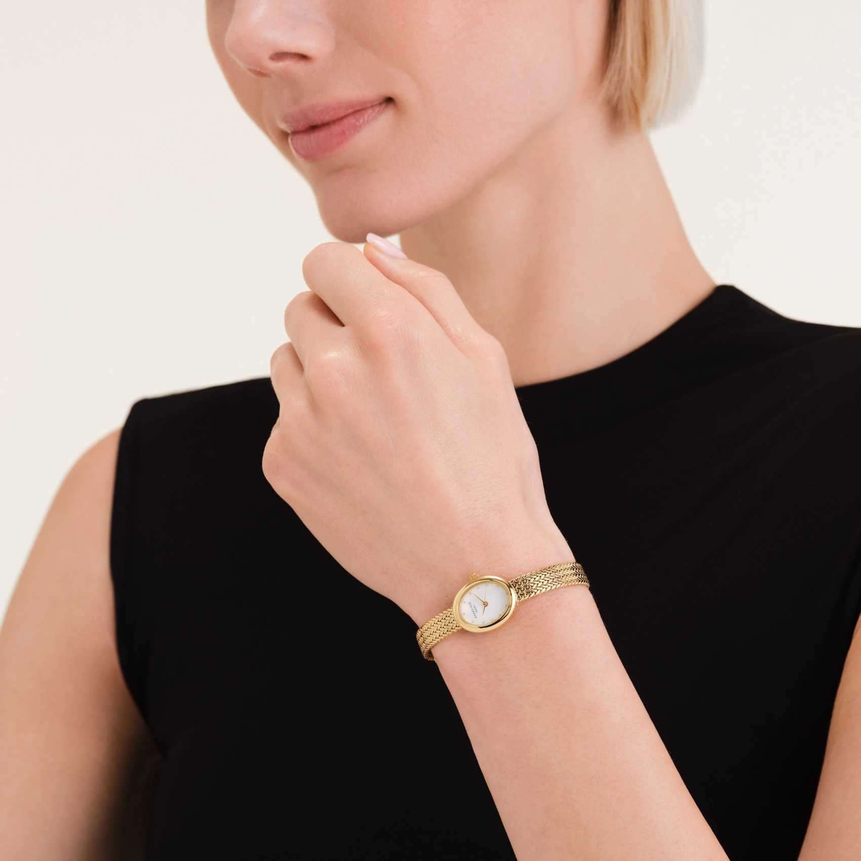 Γυναικείο ρολόι Rosefield Mini Oval Gold MWGMG-M02 με χρυσό  μπρασελέ και άσπρο φίλντισι καντράν σε οβάλ σχήμα, φορεμένο.
