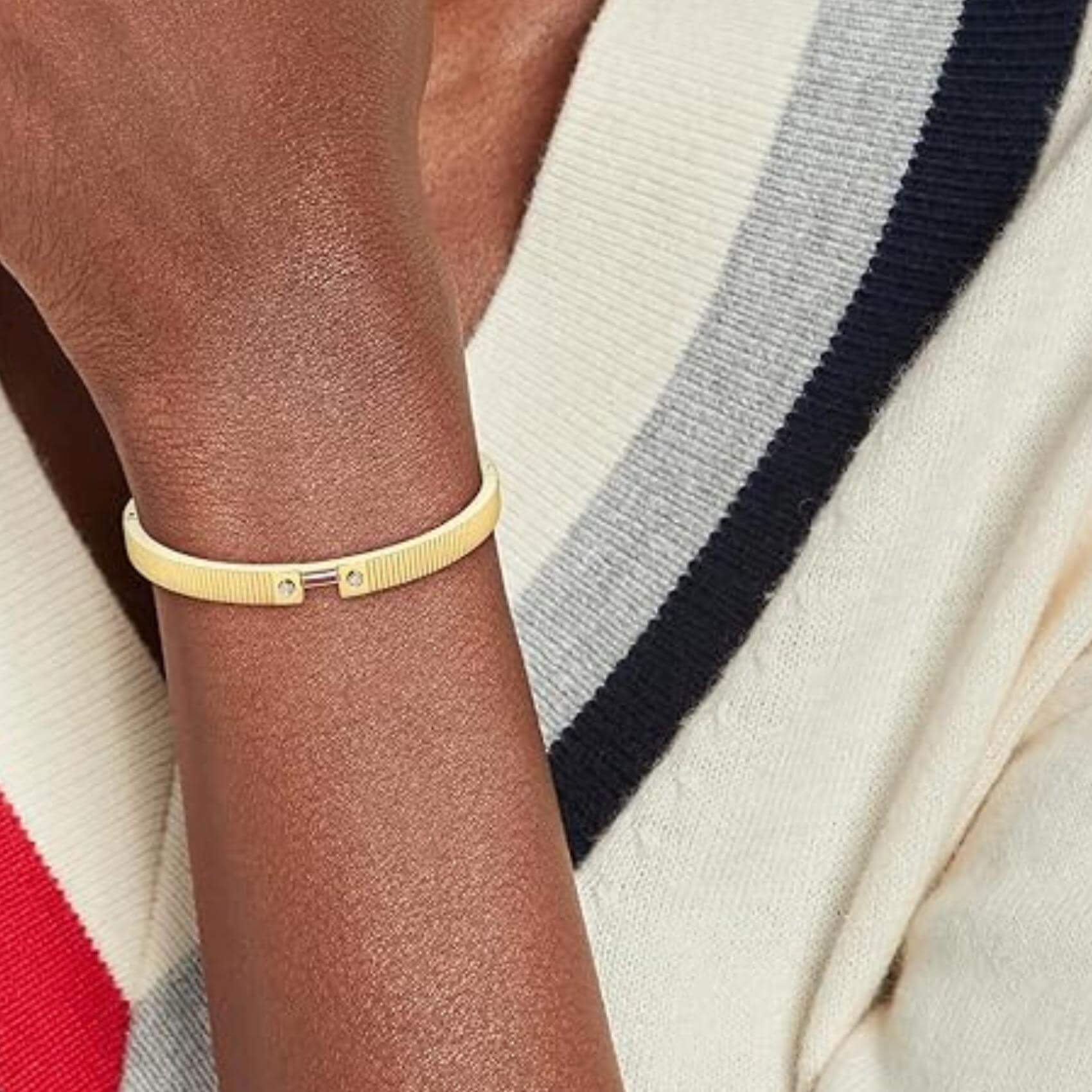Γυναικείο βραχιόλι Tommy Hilfiger Stripes 2781048 φορεμένο στον καρπό, σε χρυσό χρώμα με σχέδιο χειροπέδας.