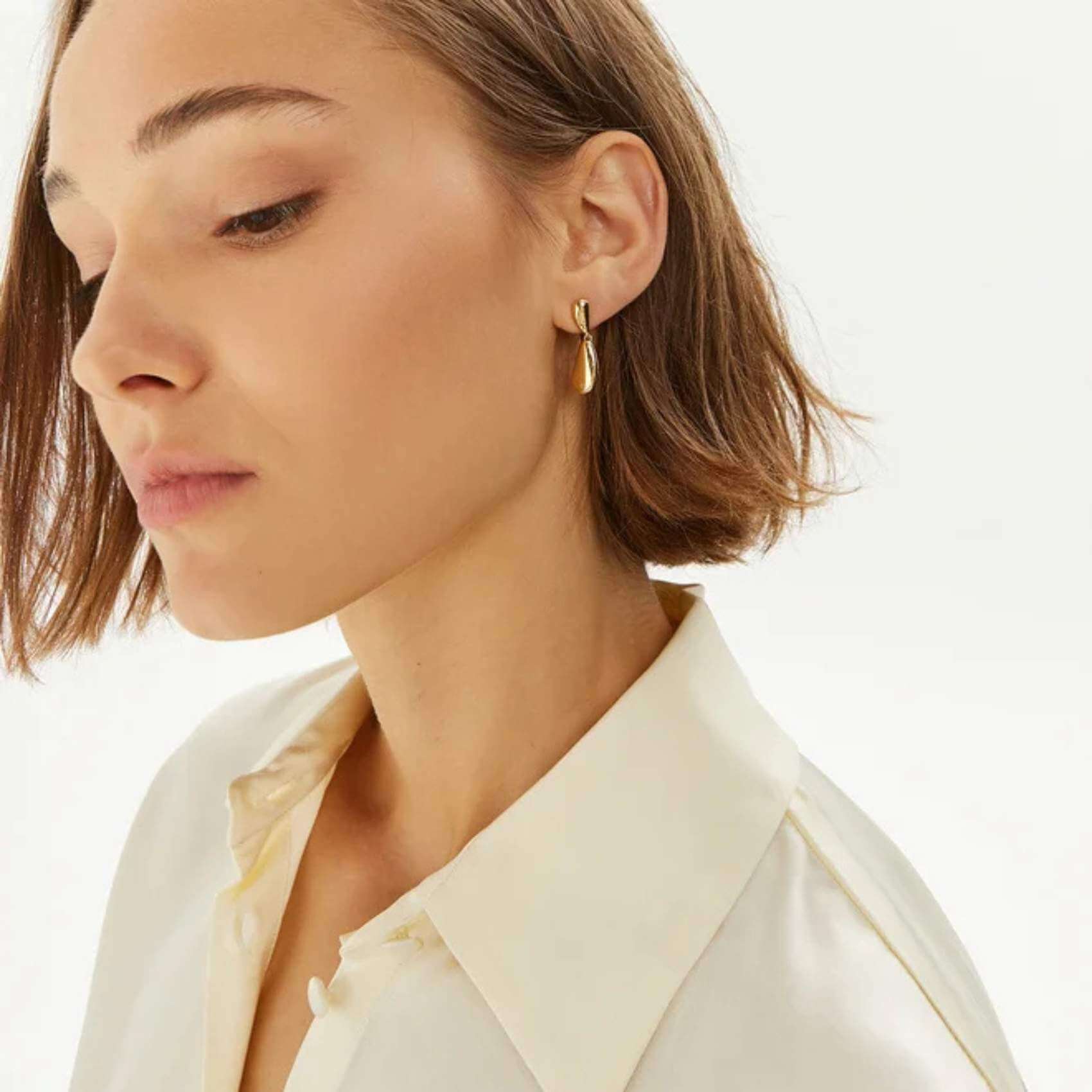 Γυναικεία καρφωτά σκουλαρίκια Calvin Klein 35000607 σταγόνες ατσάλινα σε χρυσό χρώμα, φορεμένα.