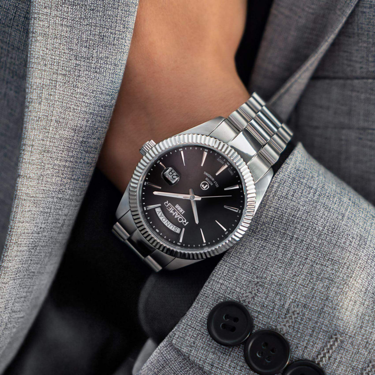 Αυτόματο ρολόι open back Roamer Primeline Day Date 981662-41-55-90 με ασημί μπρασελέ, μαύρο καντράν με ένδειξη ημέρας και ημερομηνίας και κάσα διαμέτρου 42mm.
