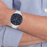 Ανδρικό ρολόι Tommy Hilfiger Henry 1710684 με ασημί ατσάλινο μπρασελέ και σκούρο μπλε καντράν διαμέτρου 43mm, φορεμένο.