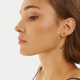 Σκουλαρίκια κρίκοι Calvin Klein 35000115 ατσάλινοι χρυσοί, φορεμένοι.