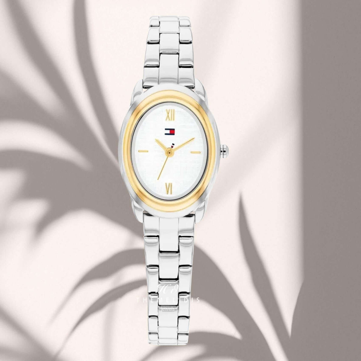 Γυναικείο ρολόι Tommy Hilfiger Demi 1782874 με λευκό οβάλ καντράν 19.7mm, χρυσούς δείκτες, χρυσή κάσα και ασημί μπρασελέ.