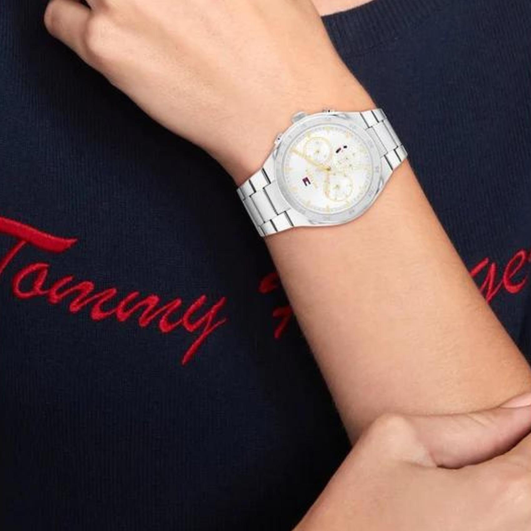 Γυναικείο ρολόι Tommy Hilfiger Carrie 1782573, με μπρασελέ σε ασημί χρώμα από ανοξείδωτο ατσάλι και λευκό καντράν με χρονογράφους και δείκτες σε χρυσό χρώμα.