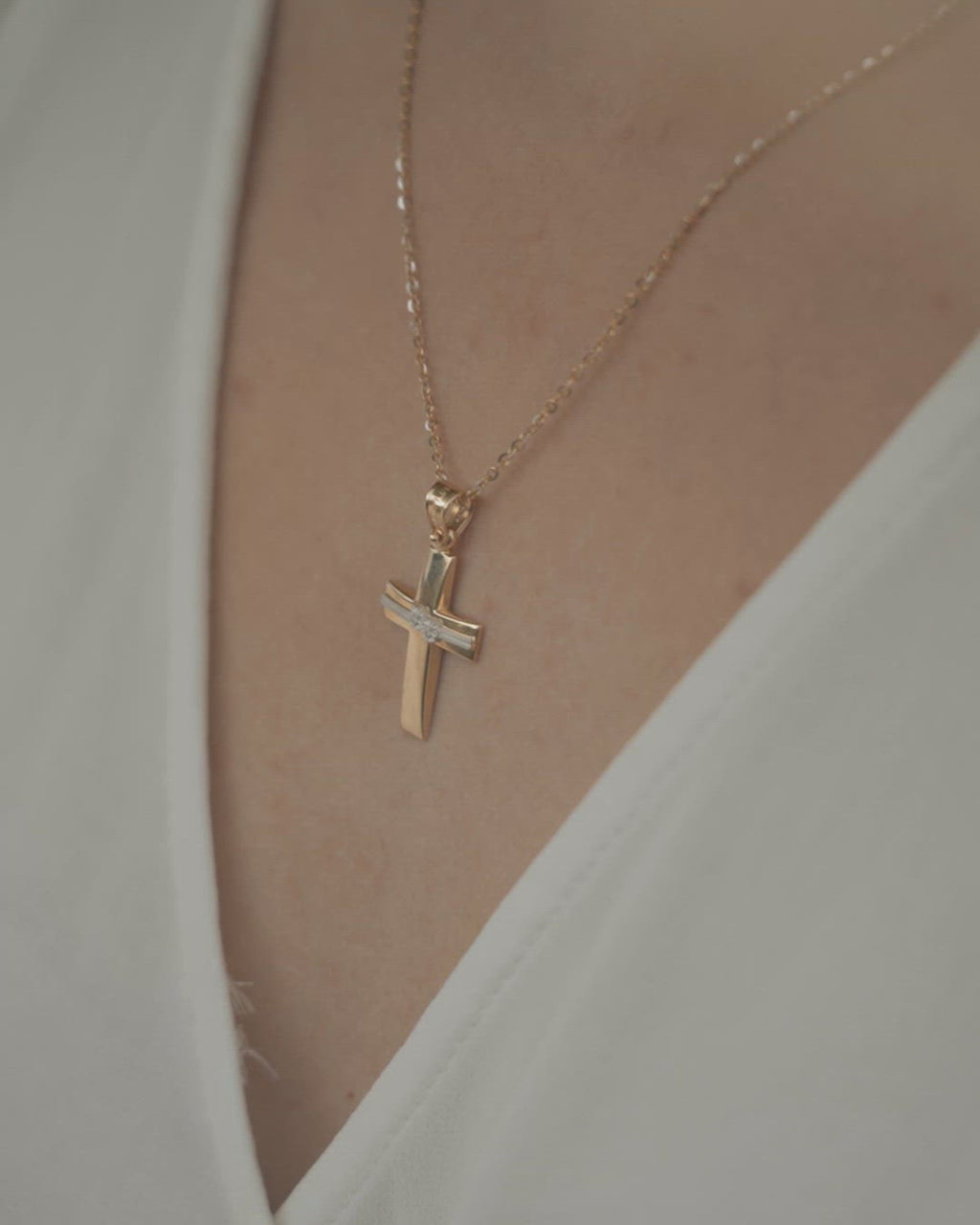 Γυναικείος σταυρός βάπτισης από χρυσό 14 καρατίων με λευκόχρυση γραμμή στη μέση και λουλούδια στολισμένα με ζιργκόν, φορεμένος σε μοντέλο. Ιδανικό δώρο για κάθε κορίτσι. 