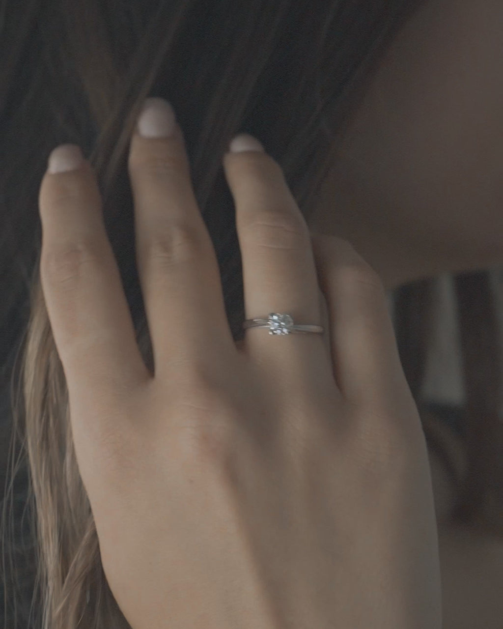 Λευκόχρυσο μονόπετρο δαχτυλίδι φλόγα με διαμάντι φορεμένο σε γυναικείο χέρι.