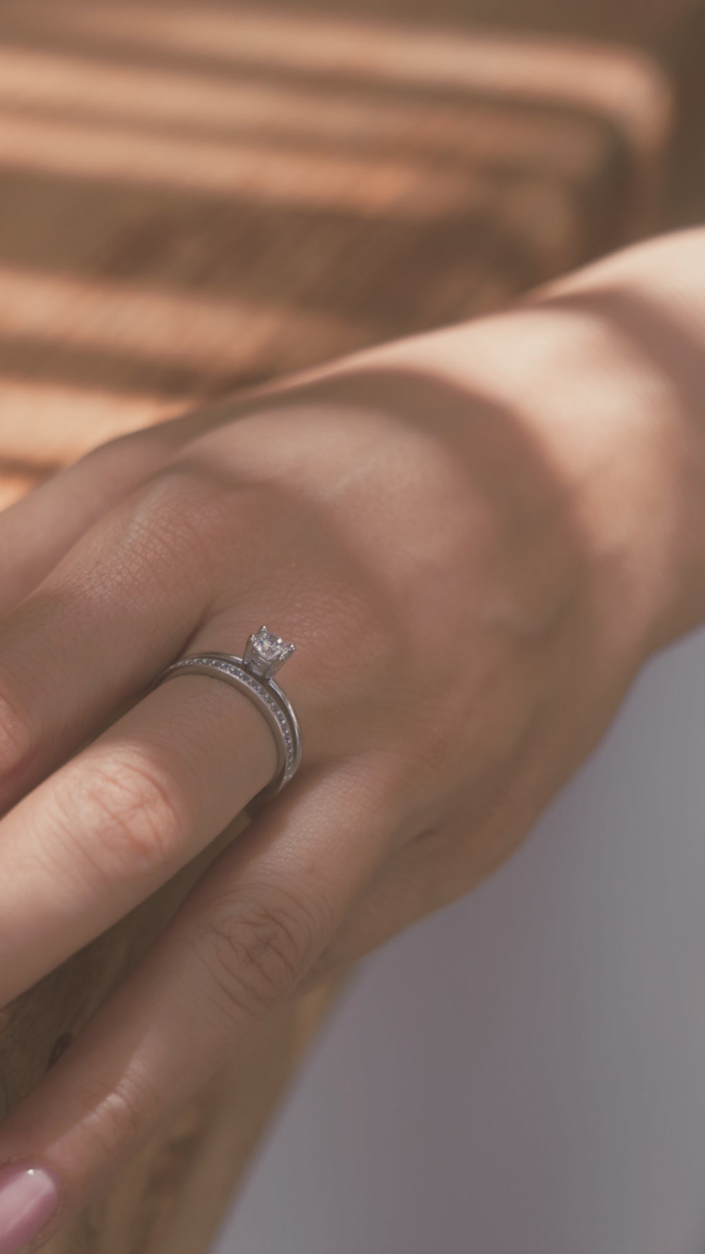 Μονόπετρο δαχτυλίδι γάμου με διαμάντι, που συνδυάζει ένα δαχτυλίδι σειρέ με διαμάντια δίνοντας την αίσθηση διπλού δαχτυλιδιού, κατασκευασμένο από λευκόχρυσο, φορεμένο σε γυναικείο χέρι.