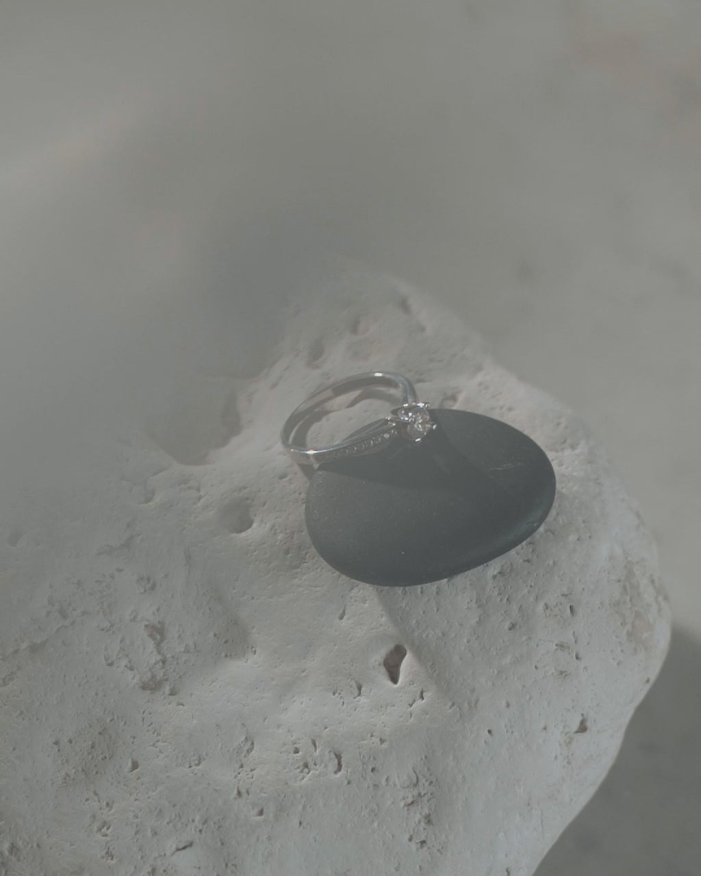 Λευκόχρυσο μονόπετρο με διαμάντι, καστόνι σε σχήμα "V" και πλαϊνές πέτρες. 