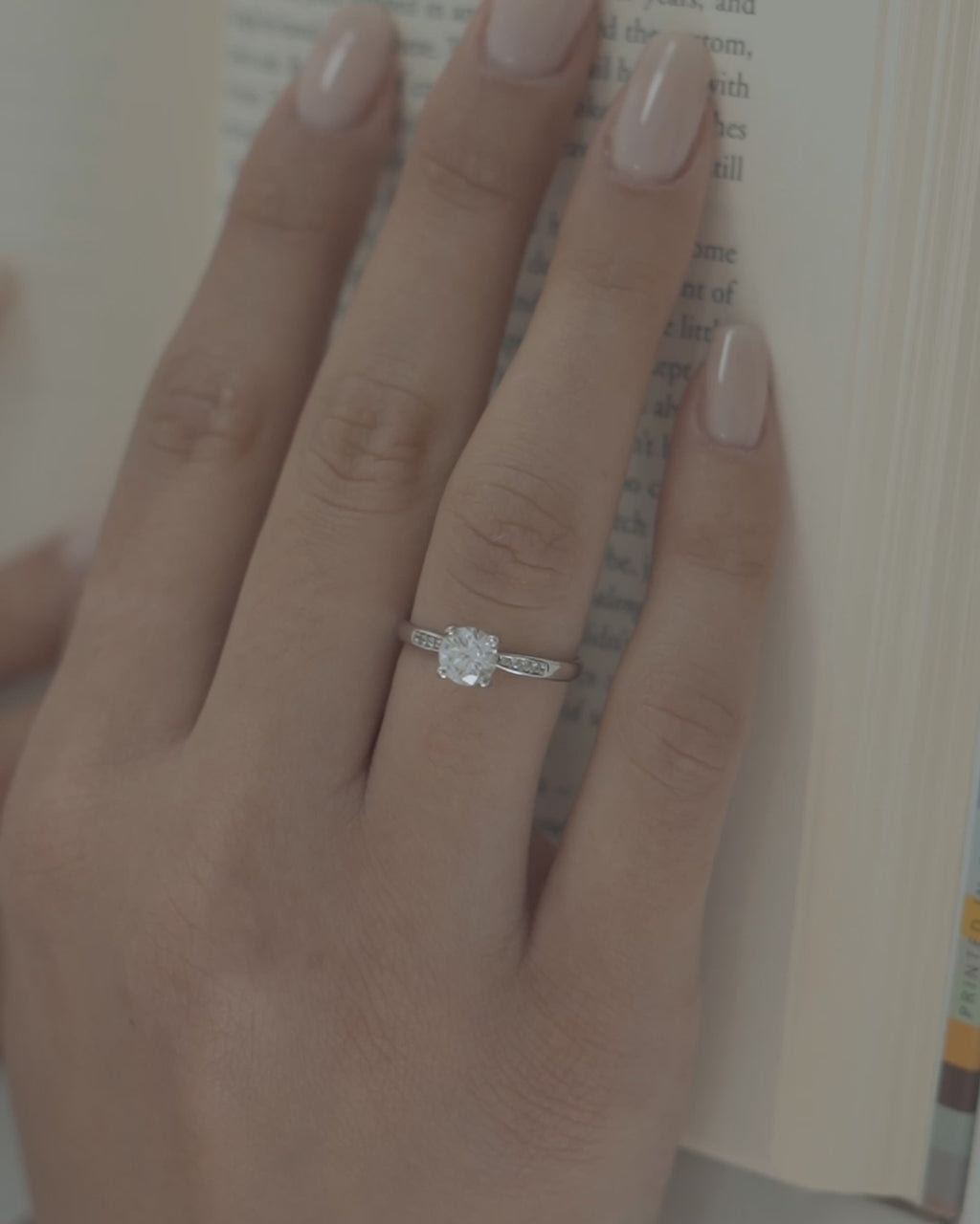 Λευκόχρυσο μονόπετρο με διαμάντι και πλαϊνές πέτρες φορεμένο σε γυναικείο χέρι.