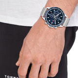 Ανδρικό ρολόι Tommy Hilfiger Miles 1792018, με μπρασελέ σε ασημί χρώμα από ανοξείδωτο ατσάλι και μπλε καντράν με χρονογράφο φορεμένο σε ανδρικό χέρι.