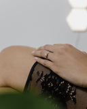 Λευκόχρυσο μονόπετρο με διαμάντι και καστόνι σε σχήμα "V" φορεμένο σε γυναικείο χέρι. 