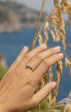 Λευκόχρυσο μονόπετρο δαχτυλίδι με διαμάντι και καστόνι σε σχήμα "V" , φορεμένο σε γυναικείο χέρι.
