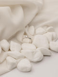 Μονόπετρο δαχτυλίδι με διαμάντι κατασκευασμένο από λευκόχρυσο και καστόνι σε σχήμα "V", επάνω σε λευκά βότσαλα.