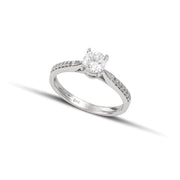 Μονόπετρο δαχτυλίδι με διαμάντι κατασκευασμένο από λευκόχρυσο, με πλαϊνές πέτρες από μικρότερα διαμάντια, φορεμένο σε γυναικείο χέρι.