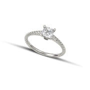 Μονόπετρο δαχτυλίδι με διαμάντι κατασκευασμένο από λευκόχρυσο με ανάγλυφες λεπτομέρειες στα πλαίνά μέρη του δαχτυλιδιού και καστόνι με τέσσερα δόντια, φορεμένο σε γυναικείο χέρι νύφης.