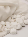 Λευκόχρυσο μονόπετρο δαχτυλίδι με διαμάντι και καστόνι με έξι δόντια, επάνω σε λευκά βότσαλα.