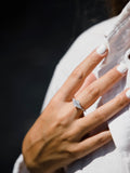 Μονόπετρο δαχτυλίδι με οβάλ κεντρικό διαμάντι και πλαίνές πέτρες από μικρότερα διαμάντια, κατασκευασμένο από λευκόχρυσο, φορεμένο σε γυναικείο χέρι.