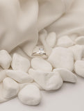 Λευκόχρυσο μονόπετρο δαχτυλίδι με διαμάντι σε τετράγωνο σχήμα baguette, επάνω σε λευκά βότσαλα.