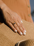 Λευκόχρυσο μονόπετρο δαχτυλίδι με διαμάντι και καστόνι σε σχήμα "V", φορεμένο σε γυναικείο χέρι.