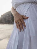 Λευκόχρυσο μονόπετρο δαχτυλίδι με διαμάντι και καστόνι σε σχήμα "V", φορεμένο σε γυναικείο χέρι.