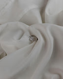 Μονόπετρο δαχτυλίδι γάμου ροζέτα με διαμάντι και πλαϊνές πέτρες brilliant κατασκευασμένο από λευκόχρυσο, επάνω σε λευκό μετάξι.