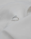 Φωτογραφία μονόπετρου δαχτυλιδιού εξάδοντο OS008 από λευκόχρυσο 14Κ με ζιργκόν σε λευκό φόντο, με κλασική λεπτή γάμπα και συμμετρικό εξάδοντο δέσιμο που αναδεικνύει τη διαχρονική λάμψη