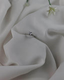 Φωτογραφία μονόπετρου δαχτυλιδιού OS002 από λευκόχρυσο 14Κ με ζιργκόν σε σατέν φόντο, με απαλές αντανακλάσεις που τονίζουν τη λάμψη των πετρών και το elegant φινίρισμα.