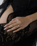 Φωτογραφία σε γυναικείο χέρι του μονόπετρου δαχτυλιδιού OS002 από λευκόχρυσο 14Κ με ζιργκόν, με σχέδιο φλόγα και πλαϊνές πέτρες που δίνουν διακριτική λάμψη για πρόταση γάμου ή ιδιαίτερη περίσταση