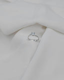 Μονόπετρο δαχτυλίδι OS004 φλόγα από λευκόχρυσο 14Κ με ζιργκόν σε λευκό φόντο, με διακριτικές αντανακλάσεις που τονίζουν τη λάμψη της πέτρας και το elegant φινίρισμα του κοσμήματος.