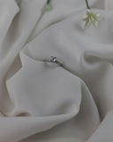 Μονόπετρο δαχτυλίδι "φλόγα" με διαμάντι και πλαϊνές πέτρες σε λευκό σεντόνι