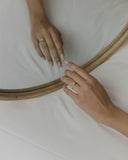 Φωτογραφία μονόπετρου δαχτυλιδιού από λευκόχρυσο 14Κ με ζιργκόν φορεμένο στο χέρι, με καστόνι φλόγας και πλαϊνές πέτρες που δίνουν κομψή λάμψη για πρόταση γάμου ή ξεχωριστή περίσταση.