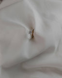 Φωτογραφία μονόπετρου δαχτυλιδιού OS007 από λευκόχρυσο 14Κ με ζιργκόν σε λευκό φόντο, με απαλές αντανακλάσεις που τονίζουν το γυαλιστερό φινίρισμα και τη διακριτική λάμψη των πλαϊνών πετρών.