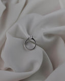 Φωτογραφία μονόπετρου δαχτυλιδιού OS020 από λευκόχρυσο 14Κ με ζιργκόν σε λευκό φόντο, με απαλές αντανακλάσεις που τονίζουν τη διακριτική λάμψη και το γυαλιστερό φινίρισμα.