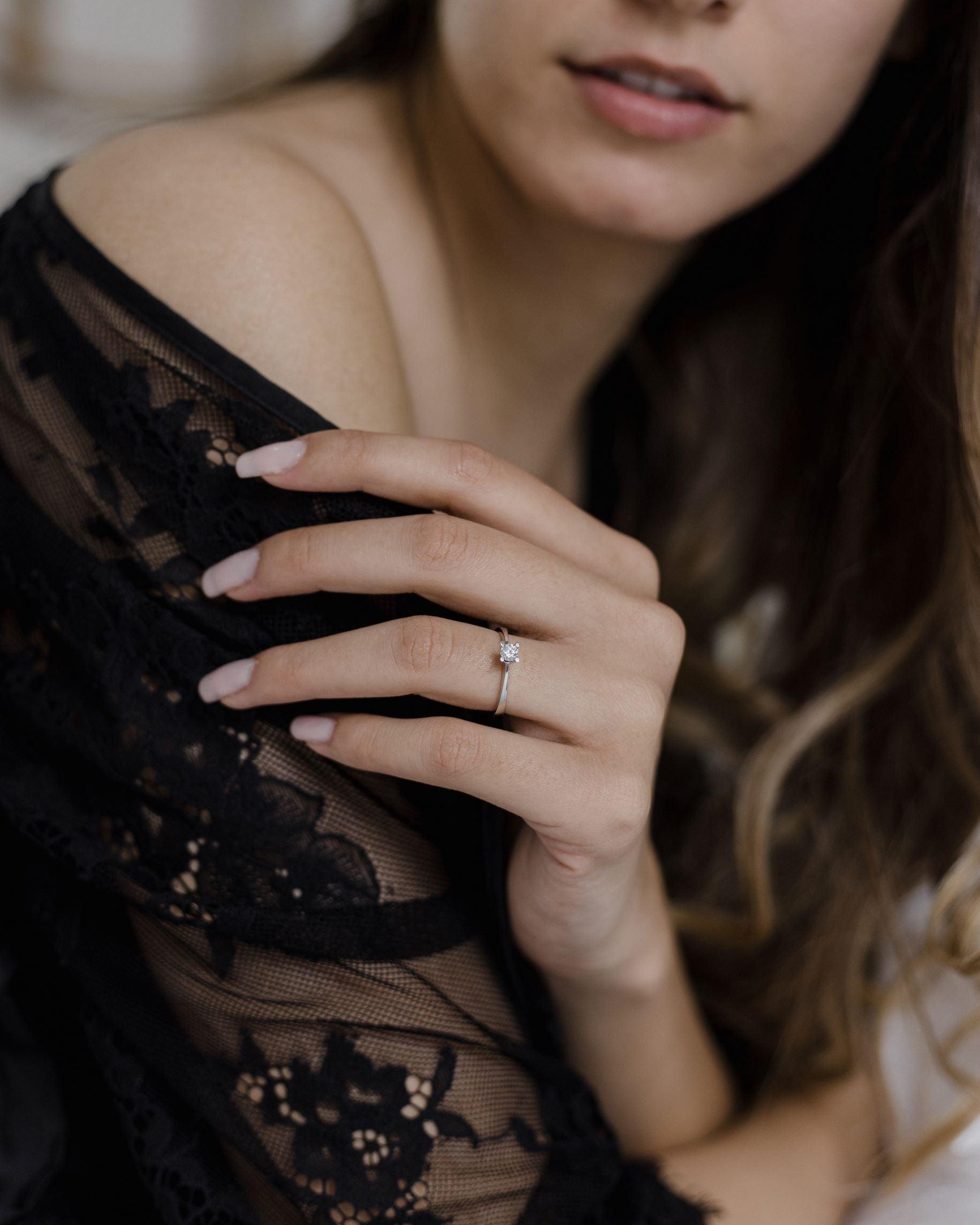 Λευκόχρυσο μονόπετρο με διαμάντι και καστόνι σχήματος V φορεμένο σε γυναικείο χέρι.