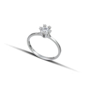 Μονόπετρο δαχτυλίδι γάμου με κεντρικό διαμάντι και πέτρες brilliant περιμετρικά κατασκευασμένο από λευκόχρυσο, φορεμένο σε γυναικέιο χέρι.