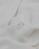 μονόπετρο δαχτυλίδι με διαμάντι και πλαϊνές πέτρες σε λευκό σεντόνι