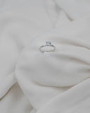 Λευκόχρυσο μονόπετρο δαχτυλίδι με διαμάντι και εξάδοντο καστόνι σε λευκό σεντόνι.