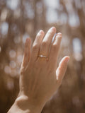 Mονόπετρο δαχτυλίδι με διαμάντι κατασκευασμένο από λευκόχρυσο με καστόνι σχήματος "V" και πλαϊνές πέτρες από μικρότερα διαμάντια, φορεμένο σε γυναικείο χέρι.