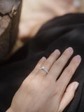 Μονόπετρο δαχτυλίδι με κεντρικό διαμάντι round cut και πλαϊνές πέτρες από μικρότερα διαμάντια, κατασκευασμένο από λευκόχρυσο φορεμένο σε γυναικείο χέρι.