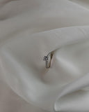 μονόπετρο δαχτυλίδι γάμου με κεντρική πέτρα από διαμάντι και πλαϊνές πέτρες κατασκευασμένο από λευκόχρυσο σε λευκό σεντόνι