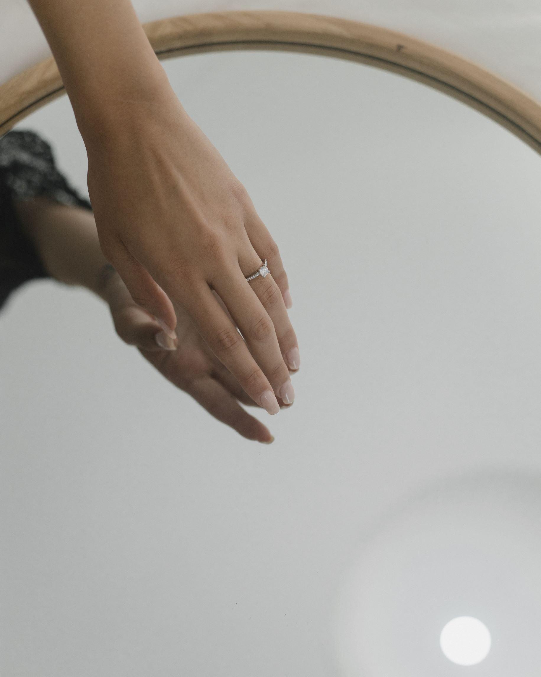μονόπετρο δαχτυλίδι αρραβώνα με ζιργκόν, κατασκευασμένο από λευκόχρυσο 14 καρατίων φορεμένο σε γυναικείο χέρι