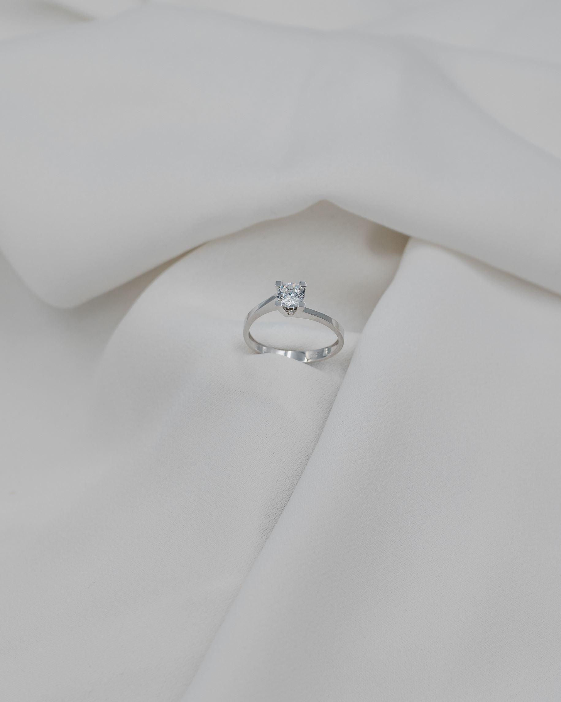 λευκόχρυσο μονόπετρο με διαμάντι σχήματος φλόγας σε λευκό σεντόνι