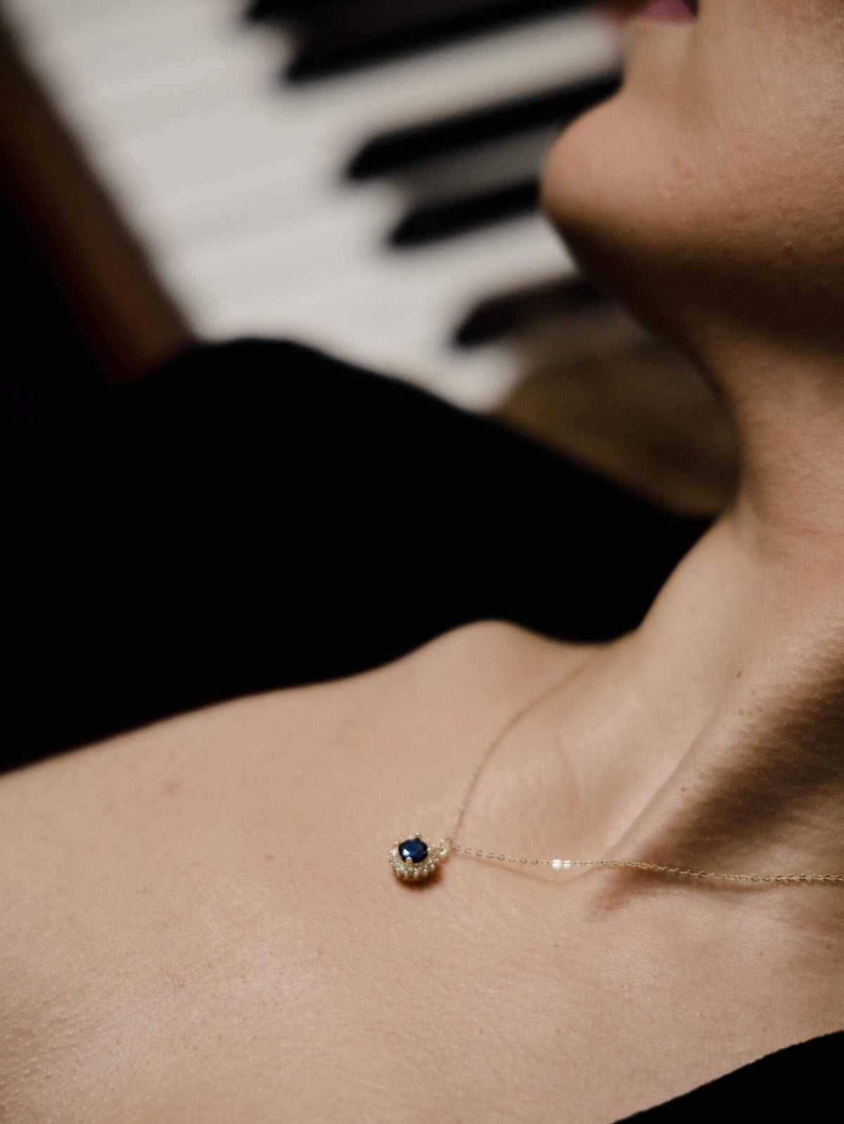 Χρυσό γυναικείο κολιέ 14Κ ροζέτα με μπλε πέτρα και λευκά ζιργκόν NL212 φορεμένο.